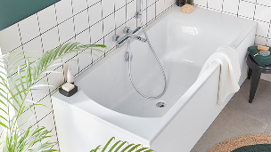 Une baignoire blanche à côté d'une plante verte.